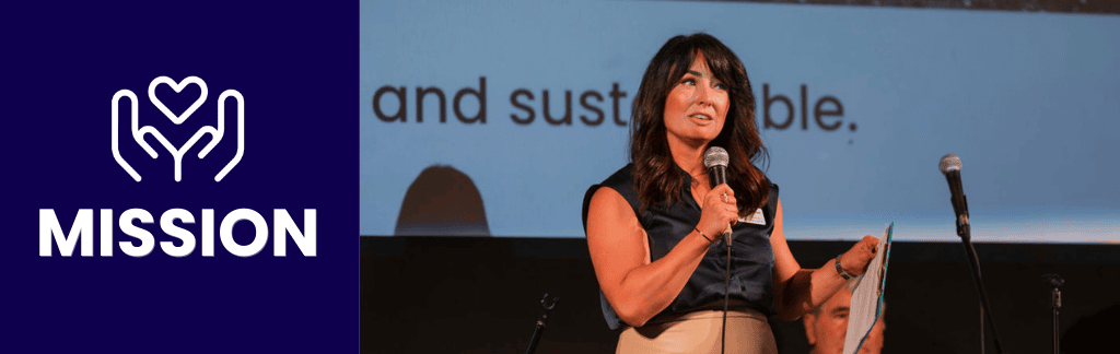 executive director addressing crowd with art in background